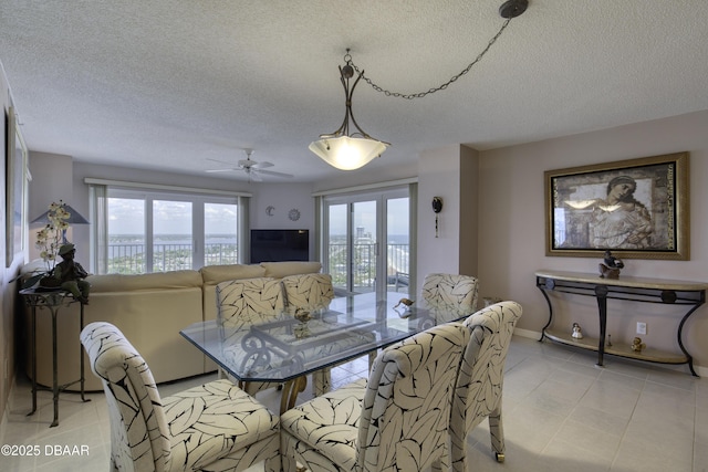 dining area with a textured ceiling, baseboards, light tile patterned floors, and ceiling fan