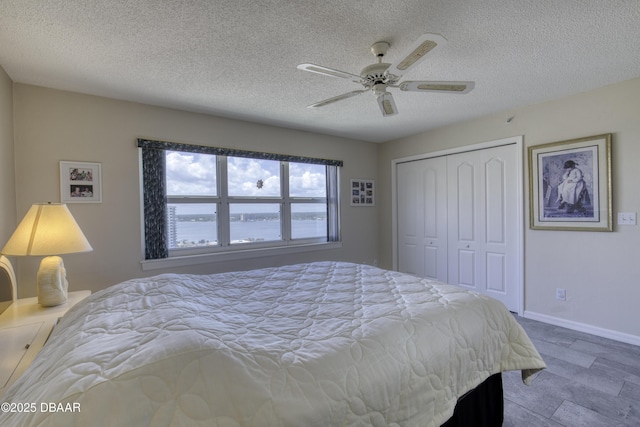 bedroom featuring baseboards, a closet, ceiling fan, and a textured ceiling