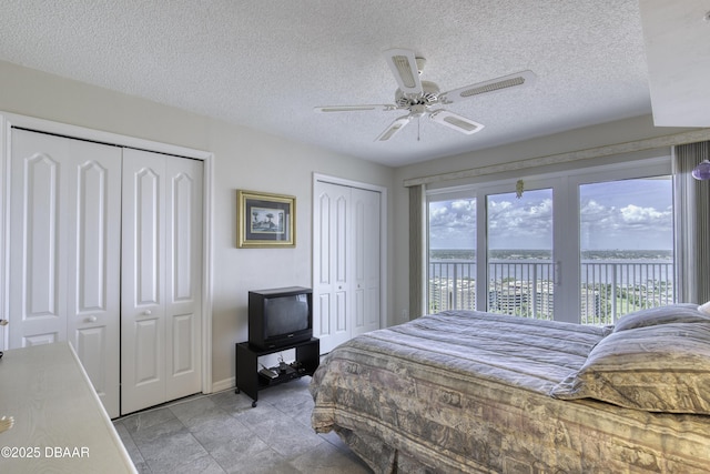 bedroom featuring two closets, a textured ceiling, access to outside, and a ceiling fan