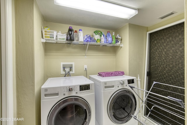 clothes washing area featuring laundry area, independent washer and dryer, visible vents, and a textured wall