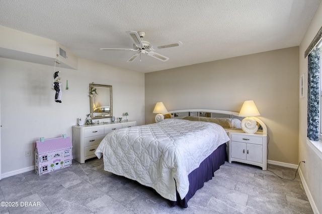 bedroom with a textured ceiling, stone finish floor, visible vents, ceiling fan, and baseboards