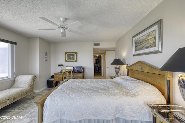 bedroom featuring a ceiling fan, a textured ceiling, baseboards, visible vents, and a spacious closet