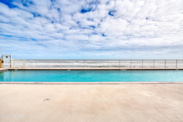 community pool with a patio and fence