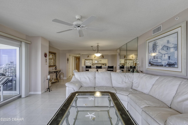 living area featuring light tile patterned floors, a textured ceiling, visible vents, baseboards, and ceiling fan