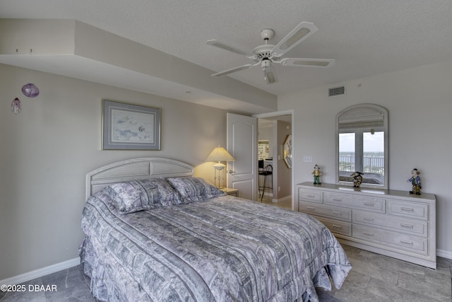 bedroom featuring baseboards, a ceiling fan, visible vents, and a textured ceiling