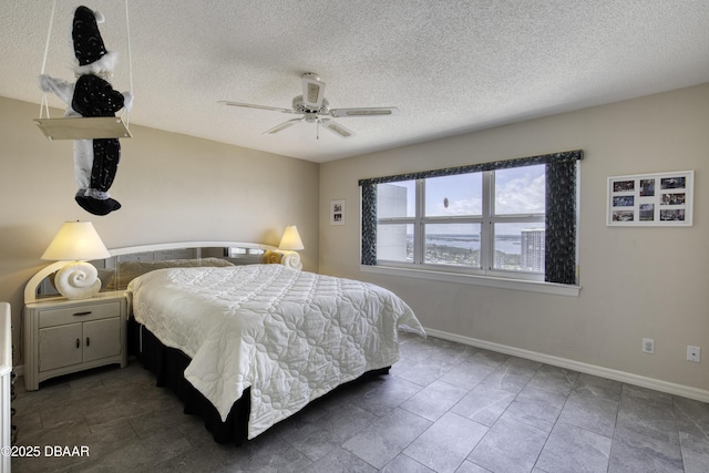 bedroom with ceiling fan, a textured ceiling, and baseboards