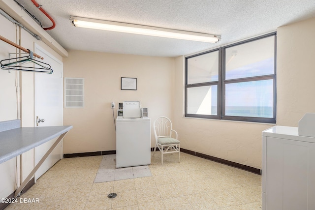 washroom featuring a textured ceiling and washing machine and clothes dryer