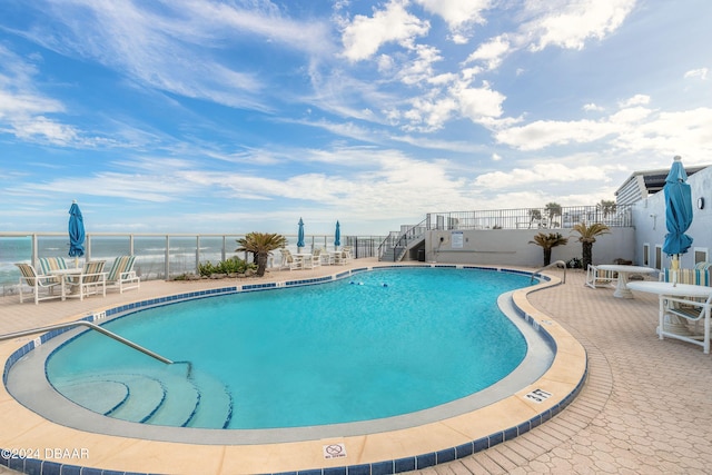 view of pool with a water view and a patio