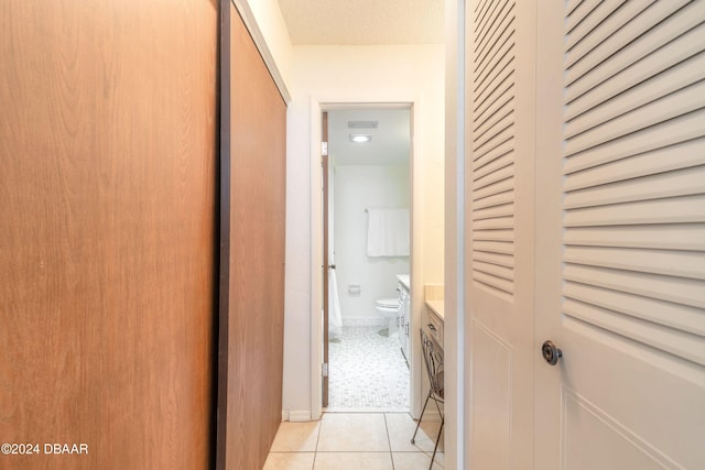 hall featuring a textured ceiling and light tile patterned floors