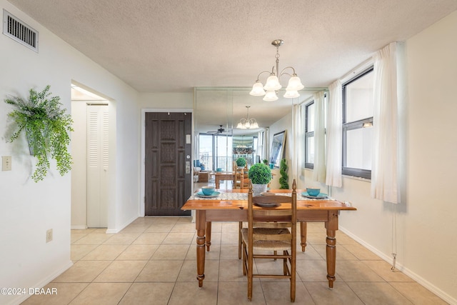 tiled dining space with a textured ceiling and a chandelier