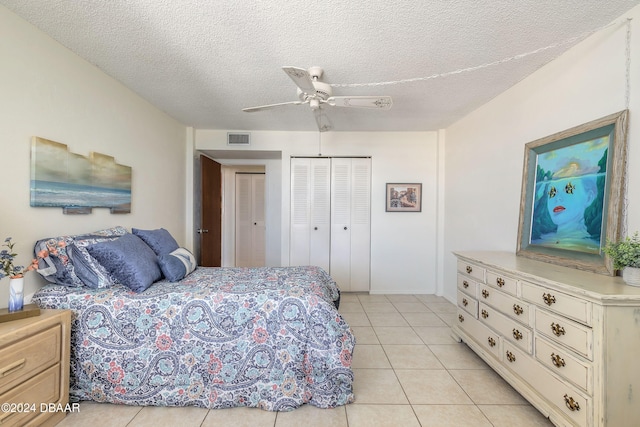 bedroom with ceiling fan, light tile patterned floors, a closet, and a textured ceiling