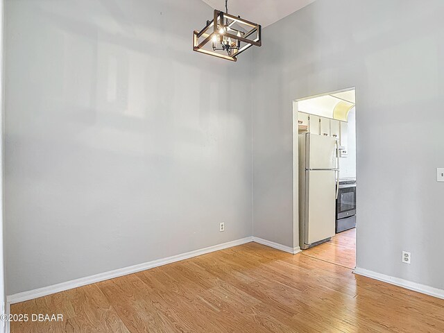 1104 Monticello Ln Unit 4, Port Orange, FL 32129 - unfurnished dining area with baseboards, light wood finished floors, and a notable chandelier