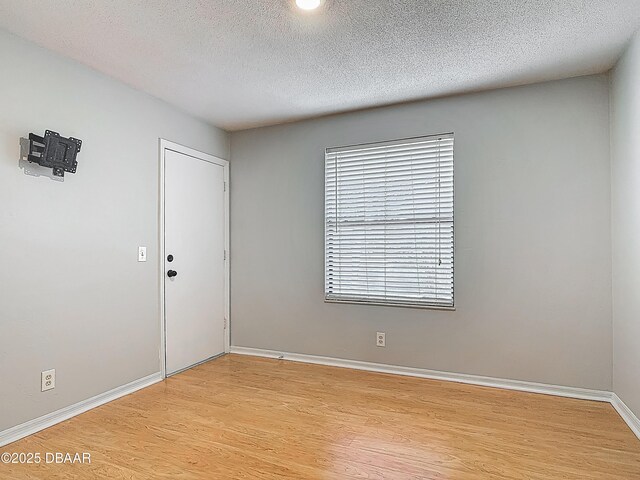 1104 Monticello Ln Unit 4, Port Orange, FL 32129 - unfurnished room featuring a textured ceiling, baseboards, and light wood-style floors