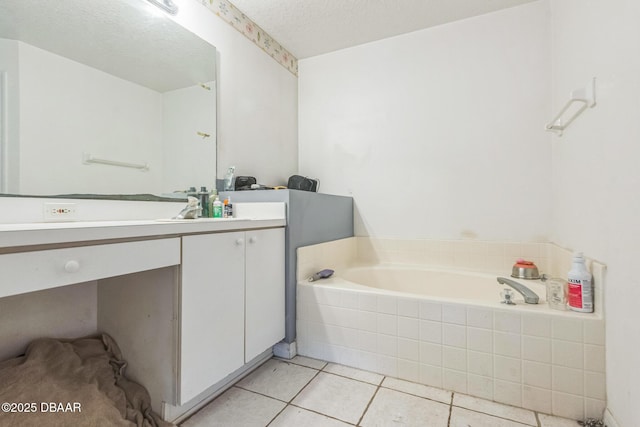 full bath with a textured ceiling, a garden tub, tile patterned floors, and vanity