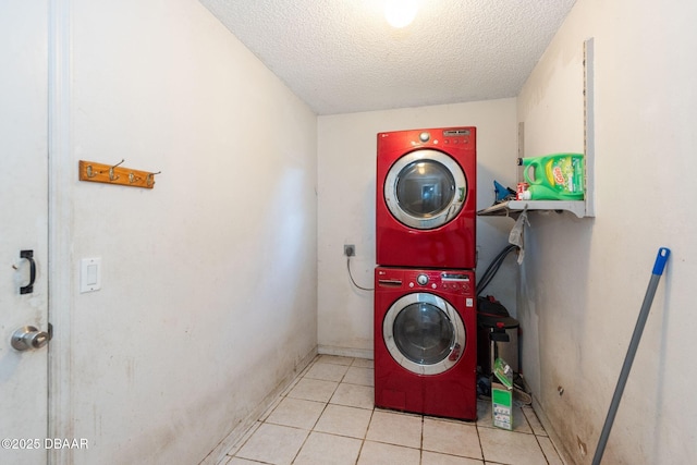 washroom featuring a textured ceiling, tile patterned flooring, stacked washer / dryer, and laundry area