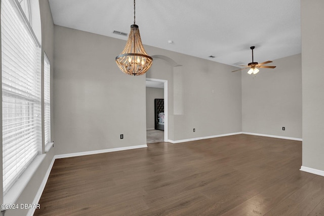 empty room featuring dark hardwood / wood-style flooring, a textured ceiling, ceiling fan with notable chandelier, and plenty of natural light