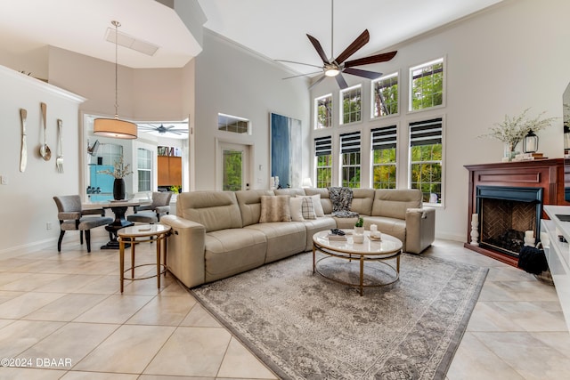 living room with a fireplace, light tile patterned flooring, a ceiling fan, and baseboards