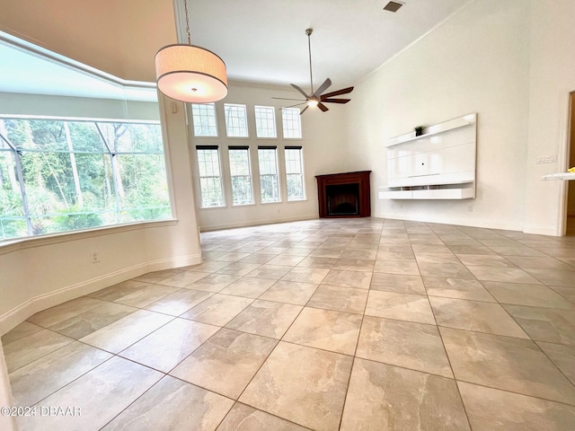 unfurnished living room with ceiling fan and a high ceiling