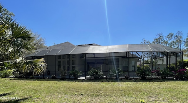 back of house with a lanai and a lawn