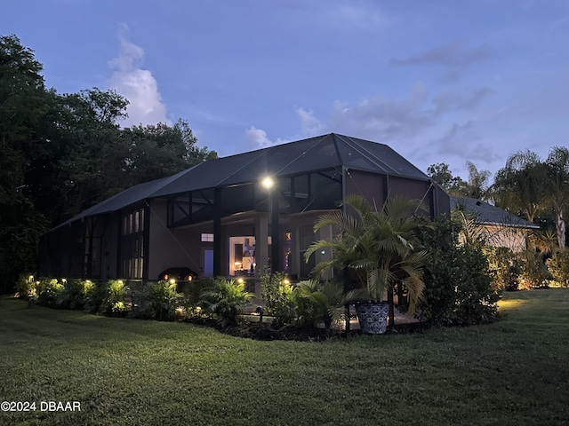 rear view of house with a lanai and a yard