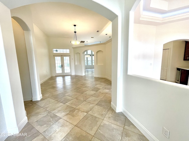 interior space featuring ornamental molding, a tray ceiling, and french doors