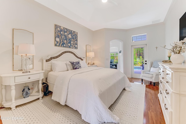 bedroom featuring access to outside, arched walkways, and light wood finished floors