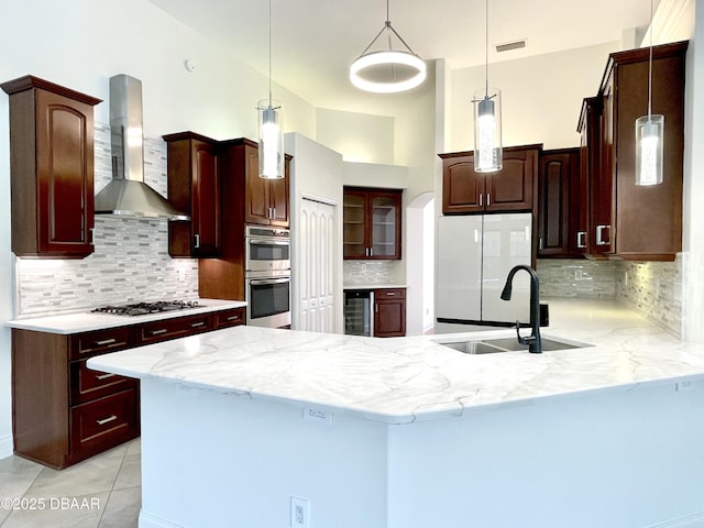 kitchen featuring visible vents, beverage cooler, a sink, a peninsula, and wall chimney exhaust hood