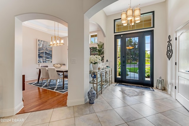 tiled foyer entrance featuring a notable chandelier and baseboards