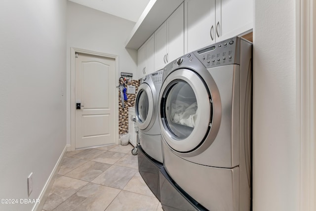 clothes washing area with washing machine and clothes dryer, light tile patterned floors, cabinet space, and baseboards