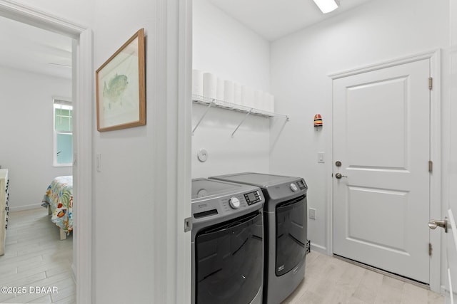 laundry area with independent washer and dryer and light hardwood / wood-style flooring