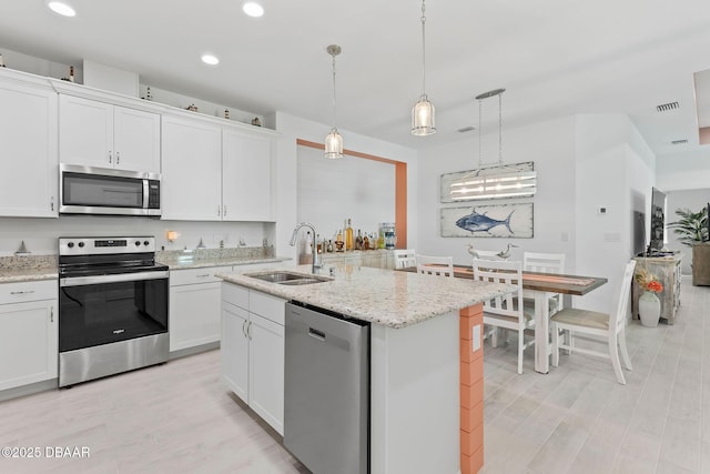 kitchen with sink, stainless steel appliances, an island with sink, and white cabinets