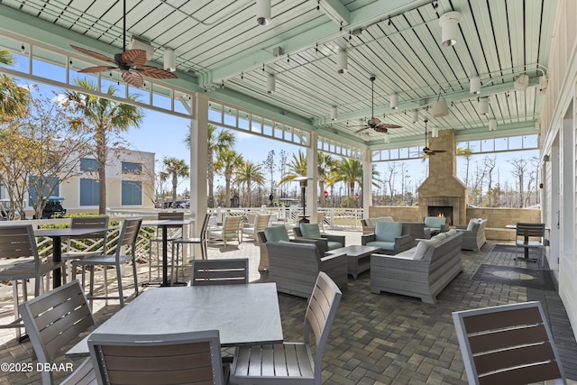 view of patio featuring ceiling fan and an outdoor living space with a fireplace