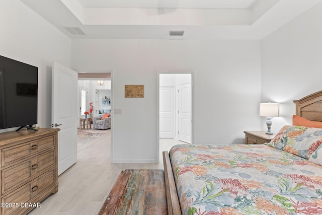 bedroom with a tray ceiling and light hardwood / wood-style flooring