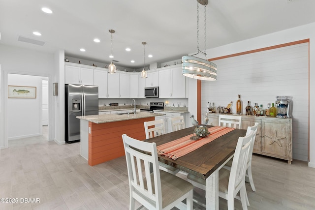 kitchen featuring sink, decorative light fixtures, stainless steel appliances, and white cabinets