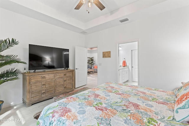 bedroom with connected bathroom and a tray ceiling