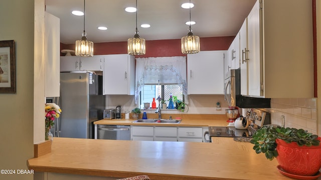 kitchen featuring sink, pendant lighting, stainless steel appliances, and white cabinets