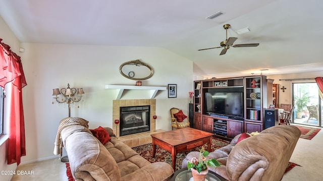 carpeted living room with ceiling fan, a tile fireplace, and lofted ceiling