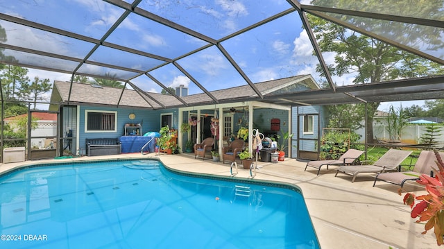 view of swimming pool with a patio, glass enclosure, and ceiling fan