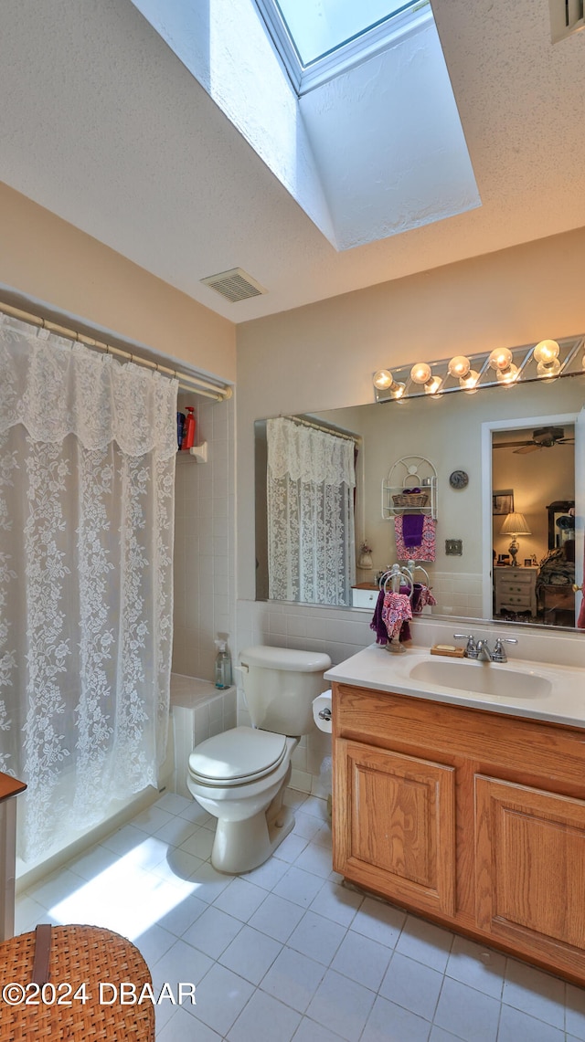 full bathroom with toilet, tile patterned floors, tile walls, a textured ceiling, and vanity