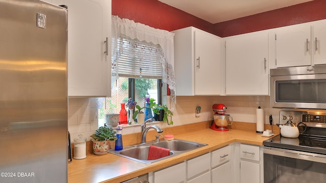 kitchen featuring white cabinets, stainless steel appliances, sink, and backsplash