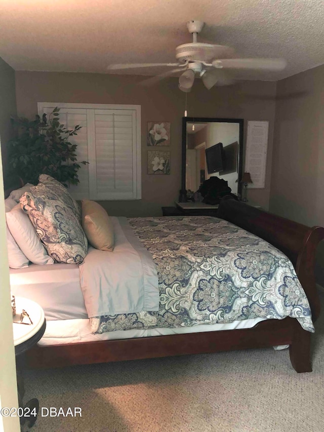 carpeted bedroom featuring ceiling fan and a textured ceiling