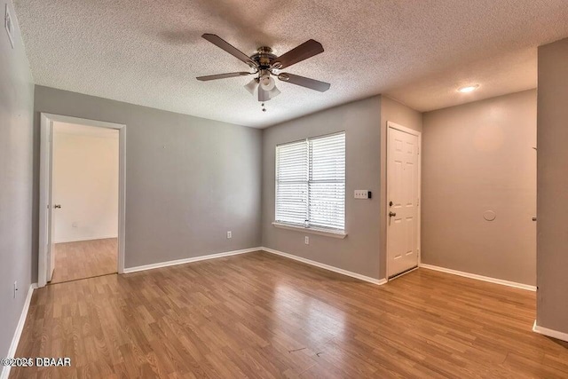 spare room featuring baseboards, wood finished floors, and a ceiling fan