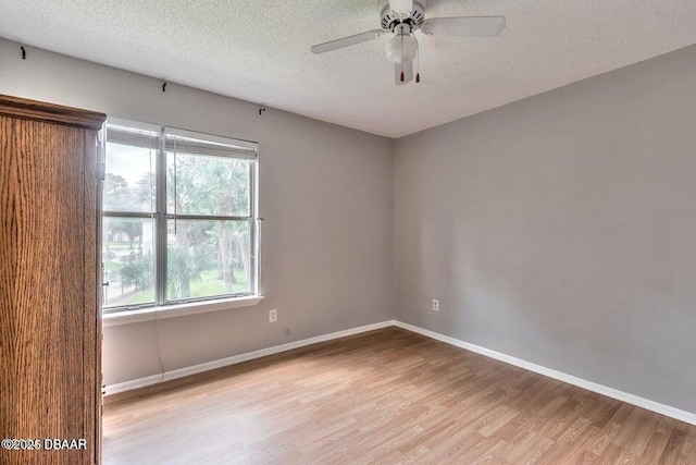 spare room with baseboards, a textured ceiling, wood finished floors, and a ceiling fan