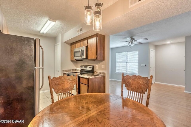 dining room with visible vents, baseboards, a textured ceiling, and a ceiling fan