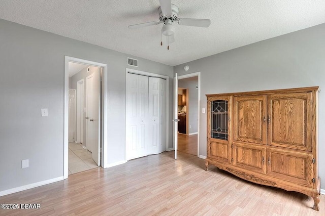 unfurnished bedroom with light wood-type flooring, visible vents, baseboards, and a textured ceiling