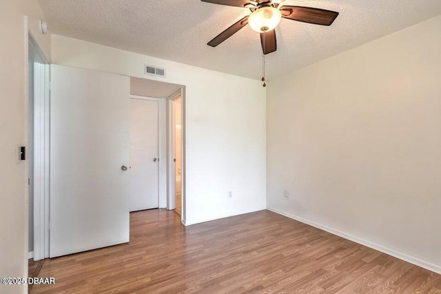 spare room with visible vents, a textured ceiling, wood finished floors, and a ceiling fan