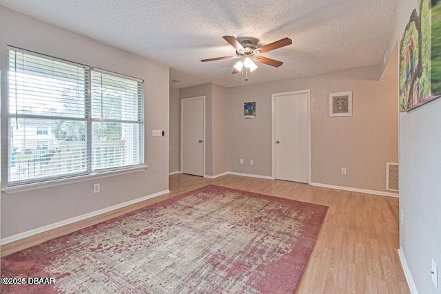 interior space with baseboards, visible vents, light wood-type flooring, and ceiling fan