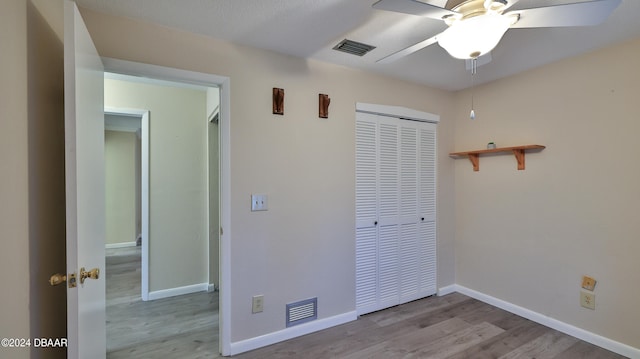 unfurnished bedroom featuring light hardwood / wood-style floors, a closet, and ceiling fan