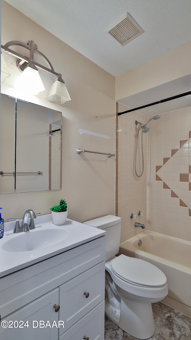 full bathroom with vanity, toilet, a textured ceiling, and tiled shower / bath combo