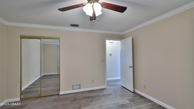 unfurnished bedroom with ceiling fan, light hardwood / wood-style flooring, crown molding, a textured ceiling, and a closet